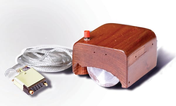 The first computer mouse: a wooden block with one red button on top, joined by a long cable to a plug.