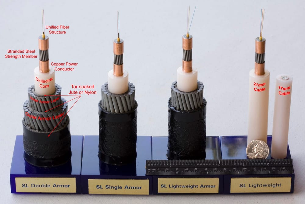 Undersea cable samples, most cut open in layers. Thin fibers stick out of a copper tube.