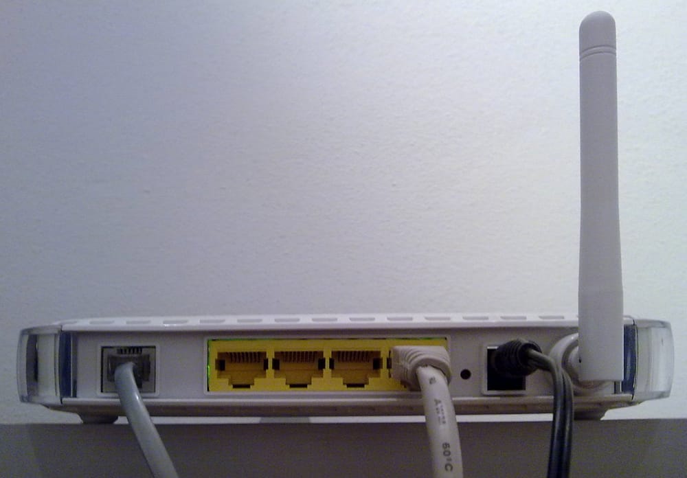 The back of a home router: a phone-line socket and four yellow network-cable sockets.